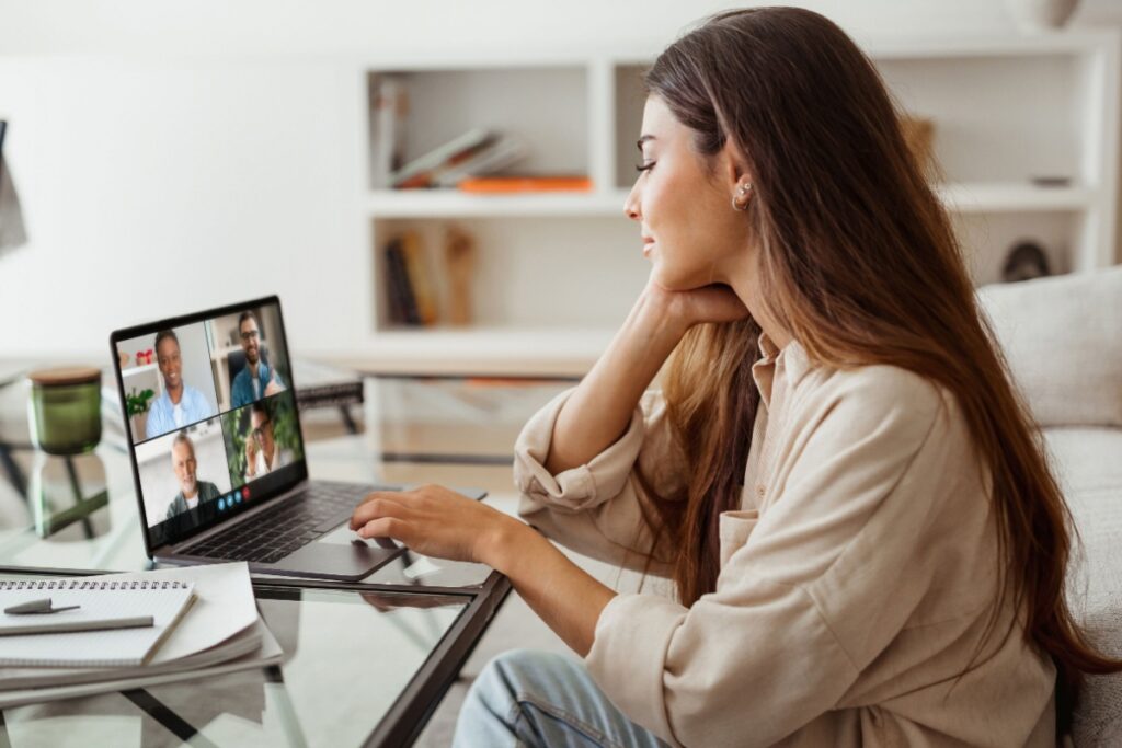 A woman sits at a desk while she has a video call on her laptop. 