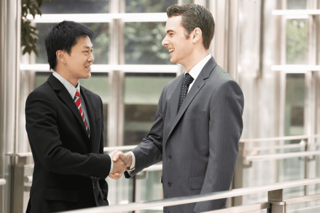 Two men in business suits smile and shake hands.