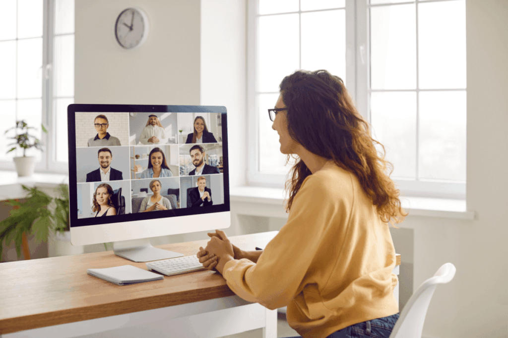 Seated woman on a video conference call with her on-screen colleagues. 