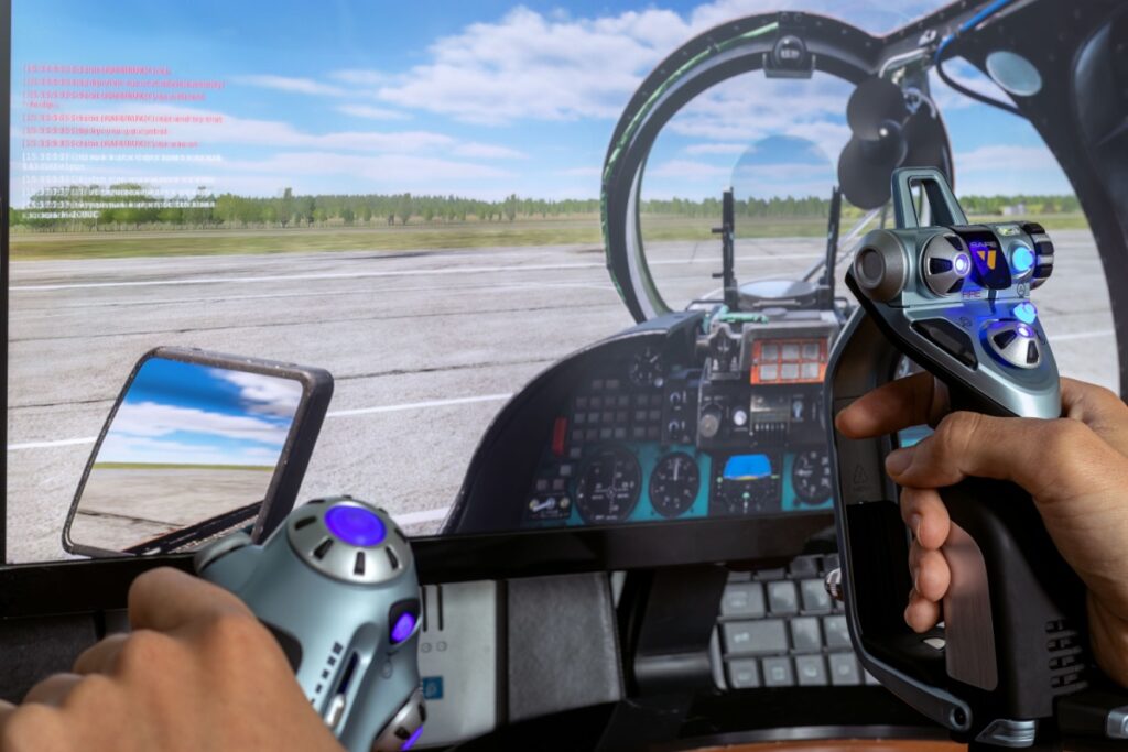 First-person view of hands on flight simulator controls, with a detailed runway scene on screen.